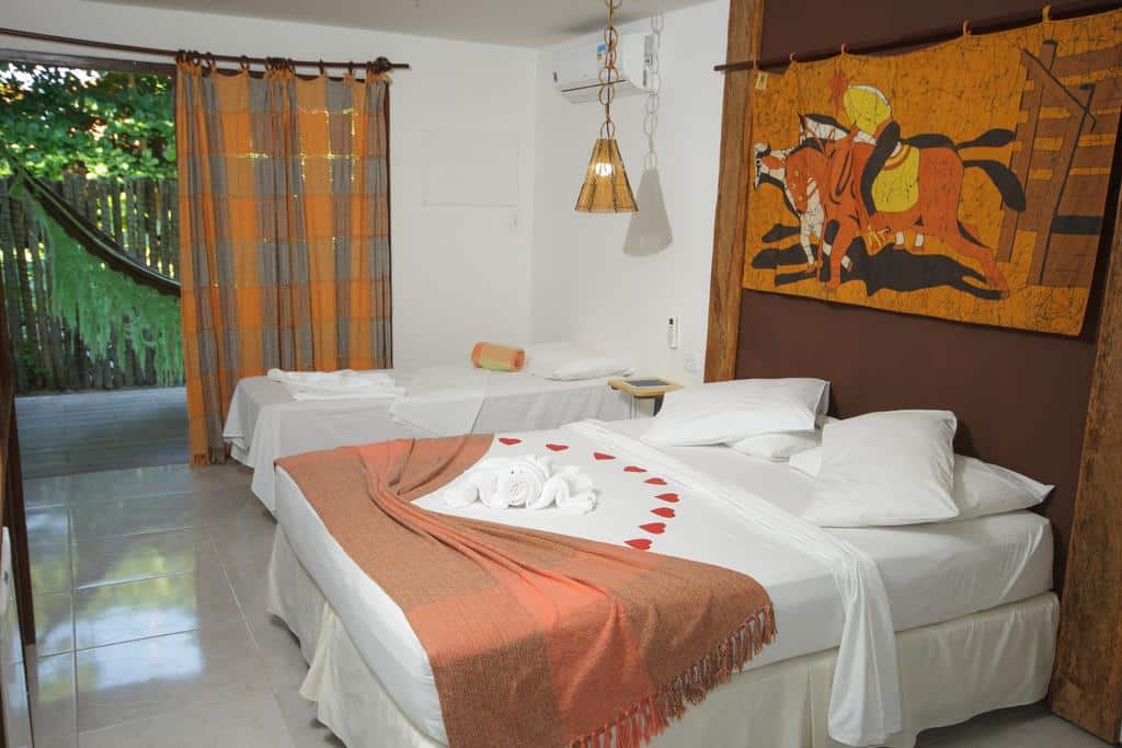 Um quarto de hotel com uma cama de casal e uma cama de solteiro, decorado com toalhas e uma pintura de cavalos acima da cabeceira da cama.