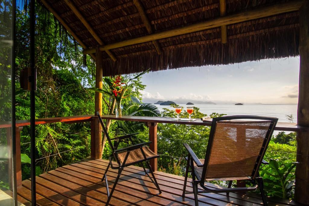 Varanda da Casa Luz virada em direção do mar com duas cadeiras e muita vegetação ao redor.