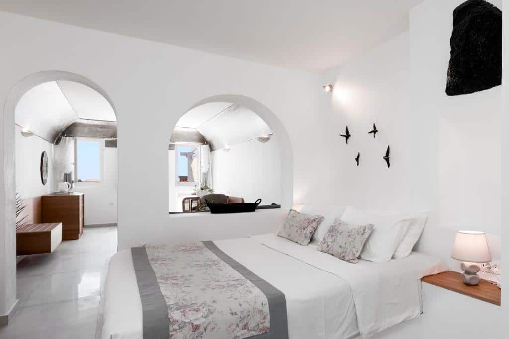 Um quarto moderno e bem iluminado com uma cama de casal, roupa de cama floral e duas aberturas em arco que levam a outro cômodo.