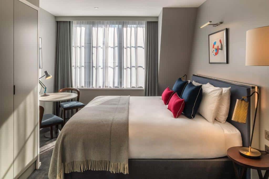 Quarto do The Resident Covent Garden com uma janela com cortinas, uma cama de casal, uma mesinha com duas cadeirinhas e um armário, para representar onde ficar em Londres.