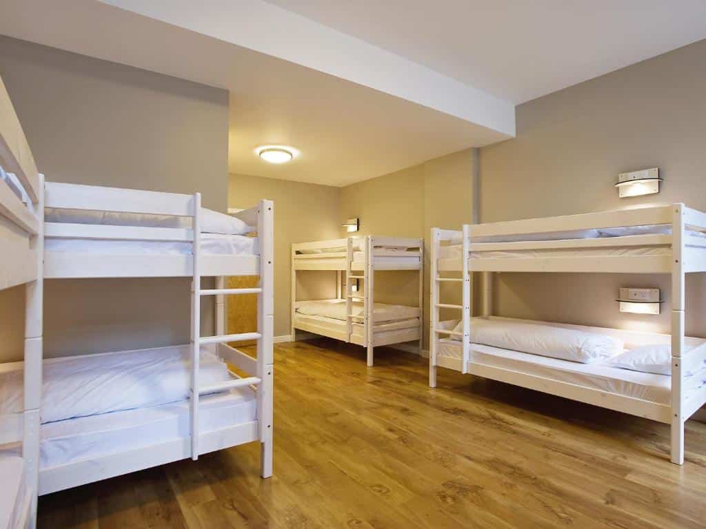 Quarto do Wombat's City Hostel London com beliches brancas e chão de madeira claro, para representar onde ficar em Londres.