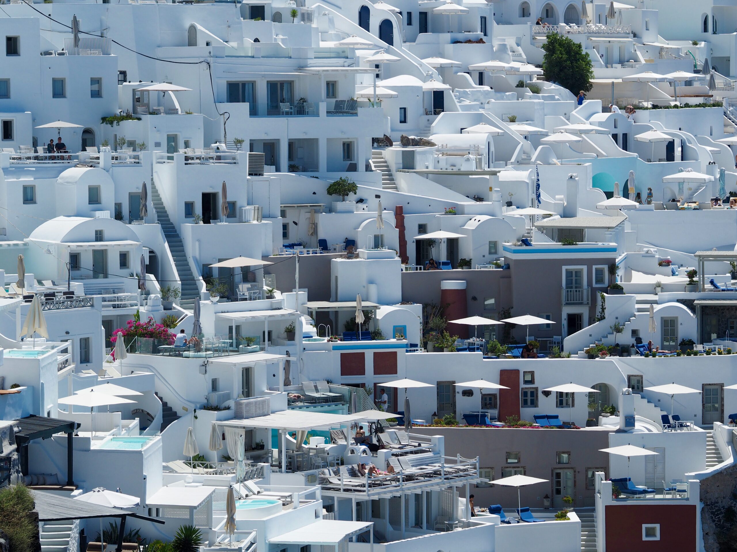 Edifícios caiados de branco com telhados planos e terraços, bem compactados em uma encosta de uma cidade costeira do Mediterrâneo.