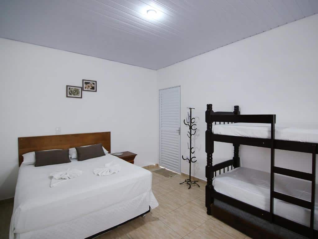 Quarto na Pousada Vale da Montanha com uma cama de casal e uma beliche, ambiente simples e novo, para representar pousadas em Serra Negra.