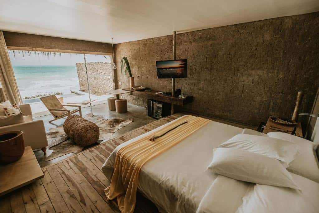 quarto do Kenoa Exclusive Beach Spa & Resort com uma cama de casal, uma sala de estar e uma varanda com piscina privativa de frente para o mar