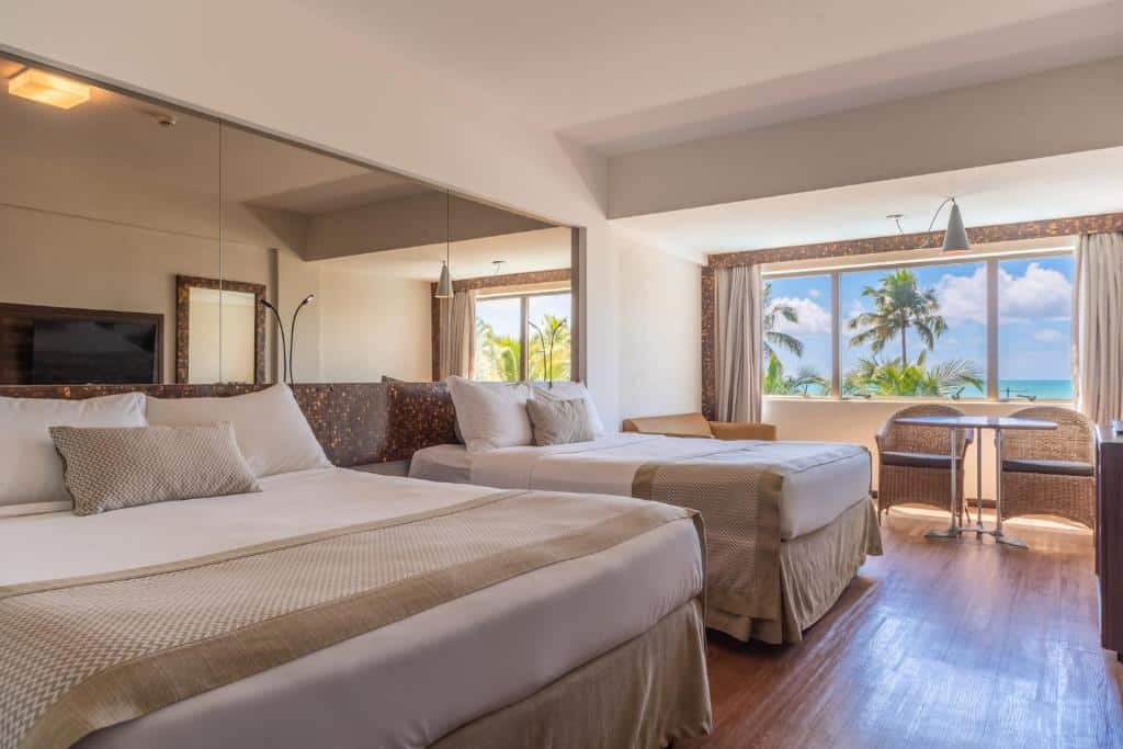 suíte do Ritz Lagoa da Anta Hotel & SPA com duas camas de casal e uma janela ampla com vista para a praia