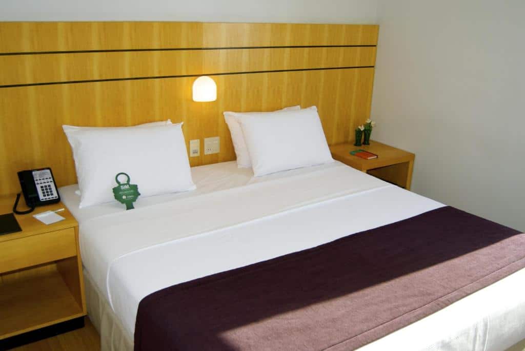 Quarto do San Diego Convention Lourdes com cama de casal e duas cômodas ao lado sendo que no lado direito há um telefone preto.