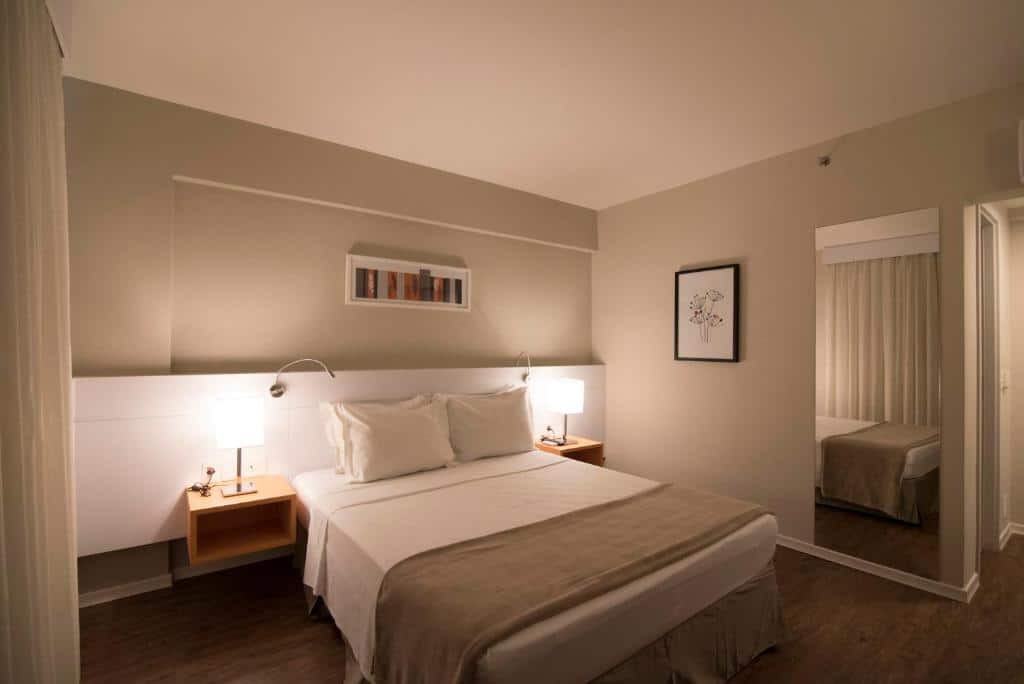Quarto do Intercity BH Exp com cama de casal, duas cômodas ao lado com luminária.