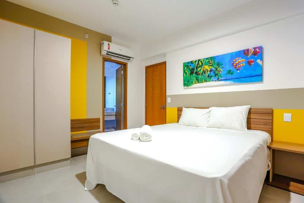 quarto do Enjoy Olimpia Park Resort com uma cama de casal, roupa de cama branca, móveis de madeira e uma pintura colorida acima da cama.