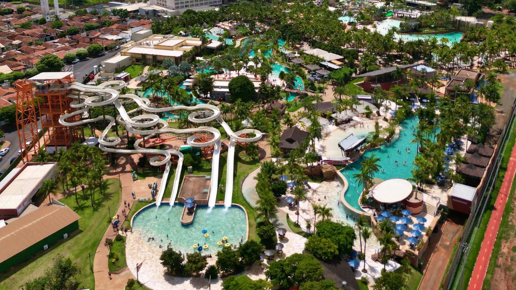 Vista aérea de um grande parque aquático com vários toboáguas sinuosos, piscinas, palmeiras e pessoas nadando.
