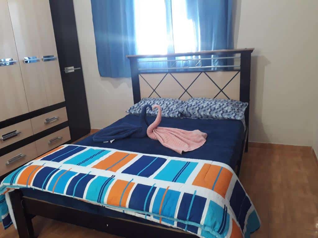Foto do quarto da Casa em São Francisco Xavier. Representa o post sobre airbnb em São Francisco Xavier. Há uma cama de casal no centro, com toalhas em cima. Na esquerda dela há um guarda-roupa, e atrás, uma janela.