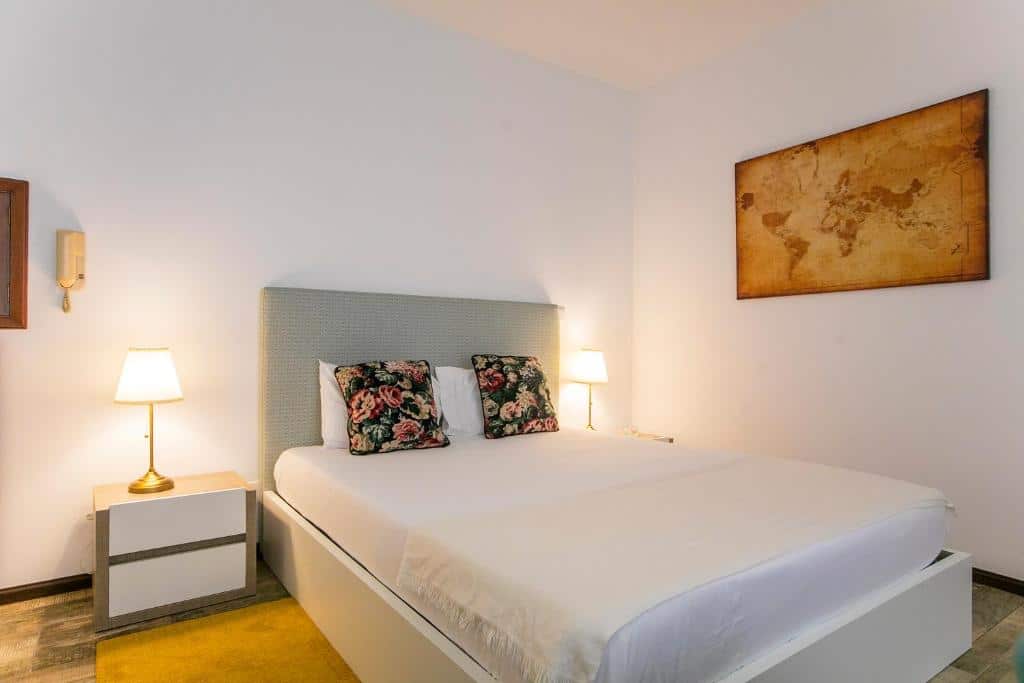 Quarto da Casa de Cristal com cama de casal do lado direito no centro do quatro com duas cômodas ao lado da cama com luminária. Representa airbnb no Porto.