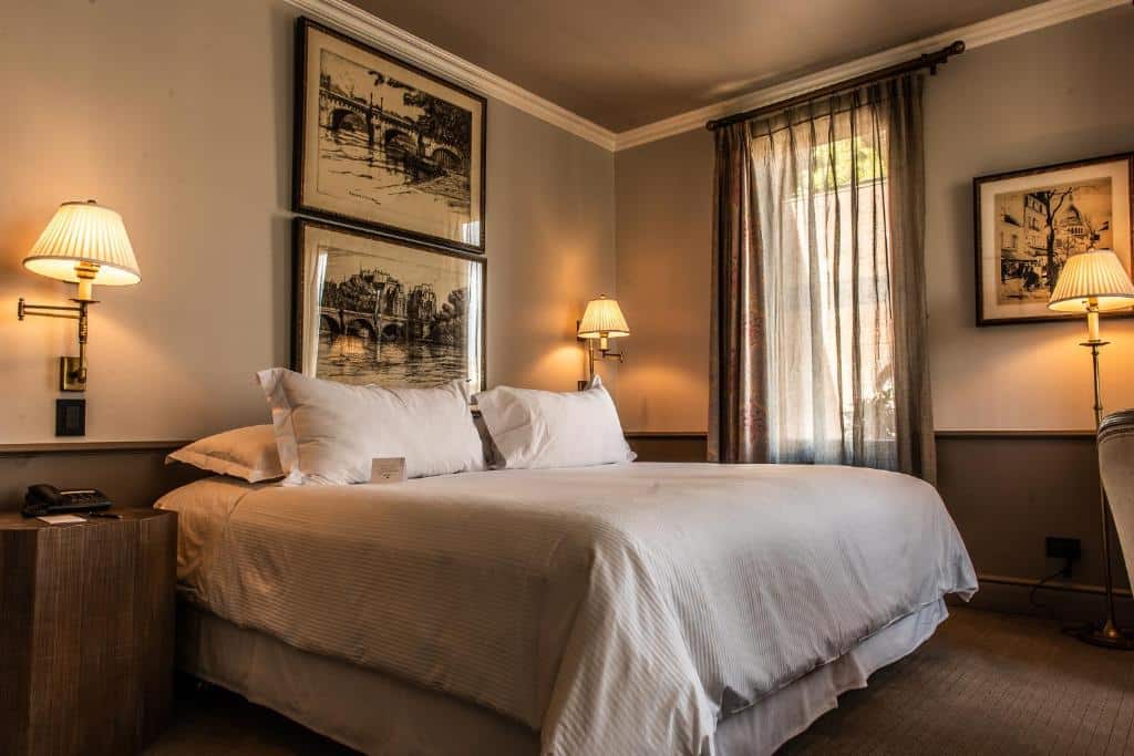 Quarto do The Singular com cama de casal e uma cômoda de madeira do lado esquerdo do quarto. Representa hotéis 5 estrelas em Santiago.