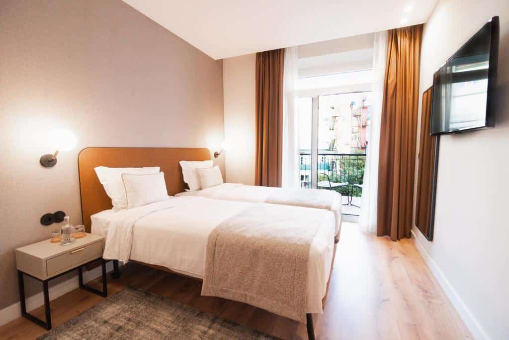 Quarto do LX SoHo Boutique Hotel by RIDAN Hotels com uma varanda com vista para a avenida, há duas camas de solteiro no local, a parede de frente para a cama tem um espelho de corpo inteiro e uma televisão