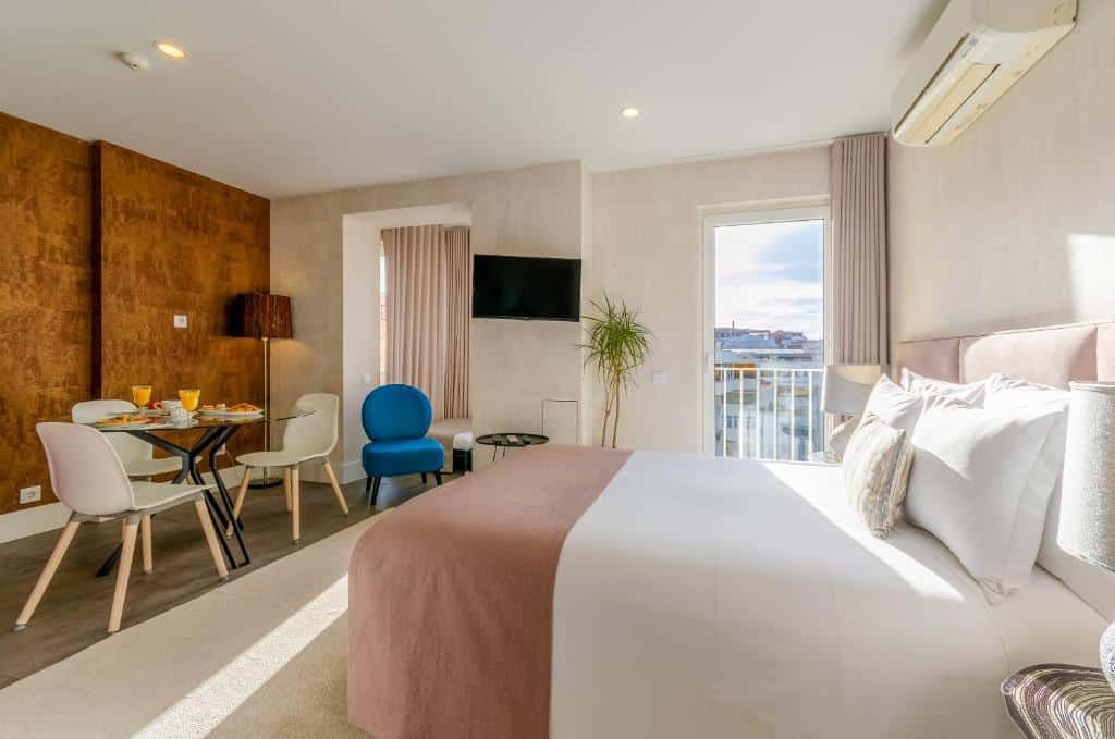 Quarto do LX51 Studios & Suites - Lisbon center com uma pequena sacada com cortinas, uma cama de casal, uma televisão, uma mesa de vidro com três cadeiras, além de uma poltrona e um abajur de chão