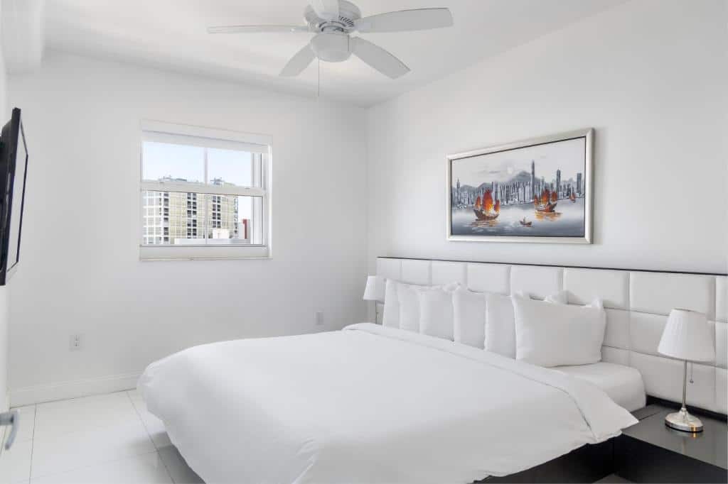 Quarto do Fortune House Hotel Suites com cama de casal, quadro acima da cama, duas cômodas com luminárias e TV em frente a cama na parede.