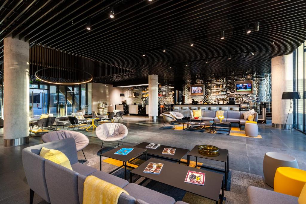 Recepção do UGO Hotel com vários sofás, poltronas e mesas de centro. Representa hotéis de luxo em Santiago.