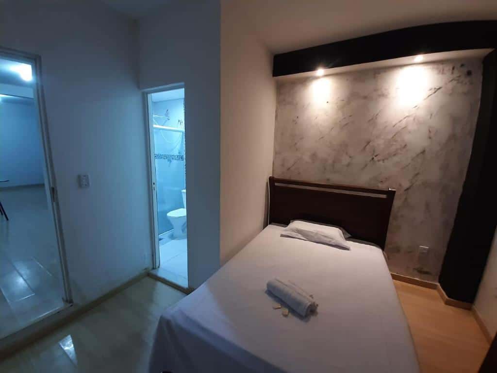 Quarto do Recanto Quitinete, com uma cama de solteiro está no meio, ao lado de duas portas, uma delas sendo a do banheiro, para representar hotéis e pousadas em Lagoa Santa.