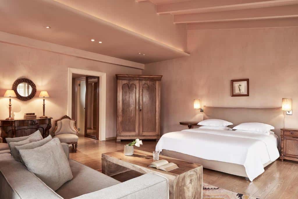 Quarto espaçoso com uma cama grande, móveis de madeira, um sofá, iluminação suave e decoração em tons neutros, no The Margi, para representar hotéis em Atenas.