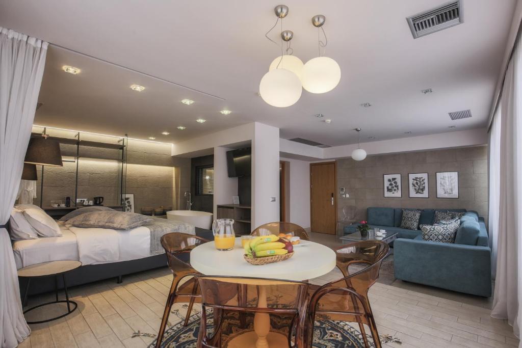 Estúdio moderno com cama, sofá, mesa de jantar, TV e luz natural de grandes janelas, no Sweet Home Hotel, para representar hotéis em Atenas.