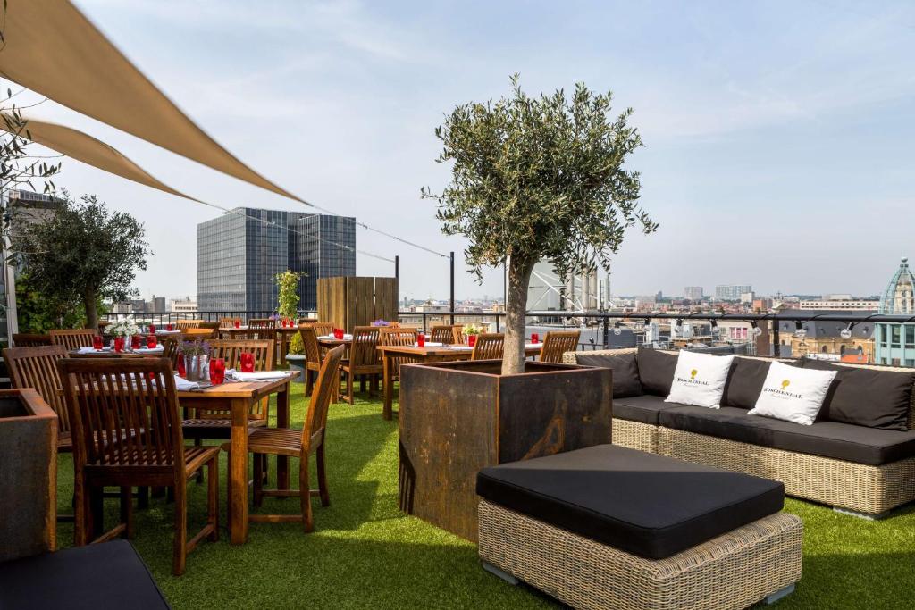terraço do NH Collection Brussels Centre um dos hotéis em Bruxelas, com sofás baixos e locais acolchoados e outras mesas e cadeiras com grama e vista dos prédios