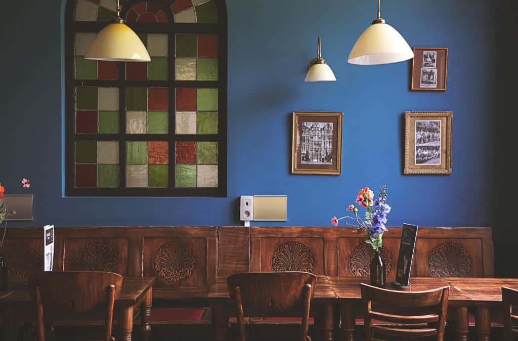 lounge com parede azul e móveis de madeira no ibis Hotel Brussels off Grand'Place, um dos hotéis em Bruxelas, com quadros coloridos na parede e luminárias brancas