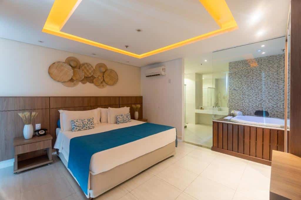 Quarto no Paraíso Corporativo com uma cama de casal, banheira de hidromassagem e luz de led no teto, para representar hotéis em Cabo Frio.