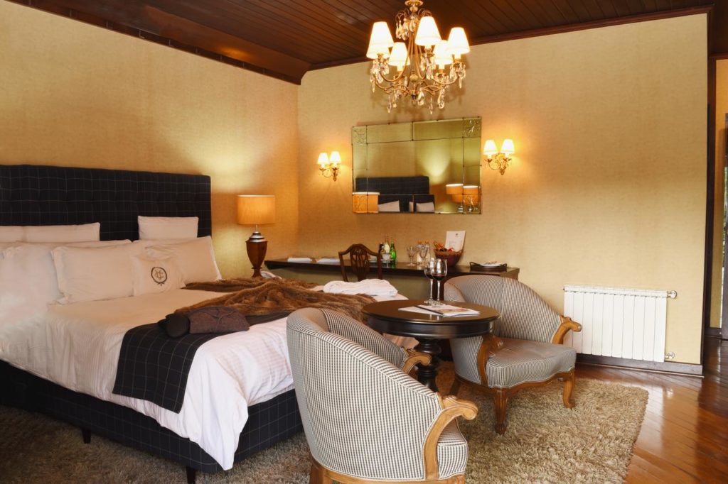 Um quarto na Villa Casato Resdenza Boutique com uma cama de casal, duas poltronas, uma mesa, uma escrivaninha, luminárias e um lustre.