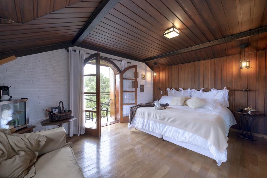Quarto no WE Hotel com paredes e teto de madeira, uma cama grande, portas duplas que dão para uma varanda e entrada de luz natural.