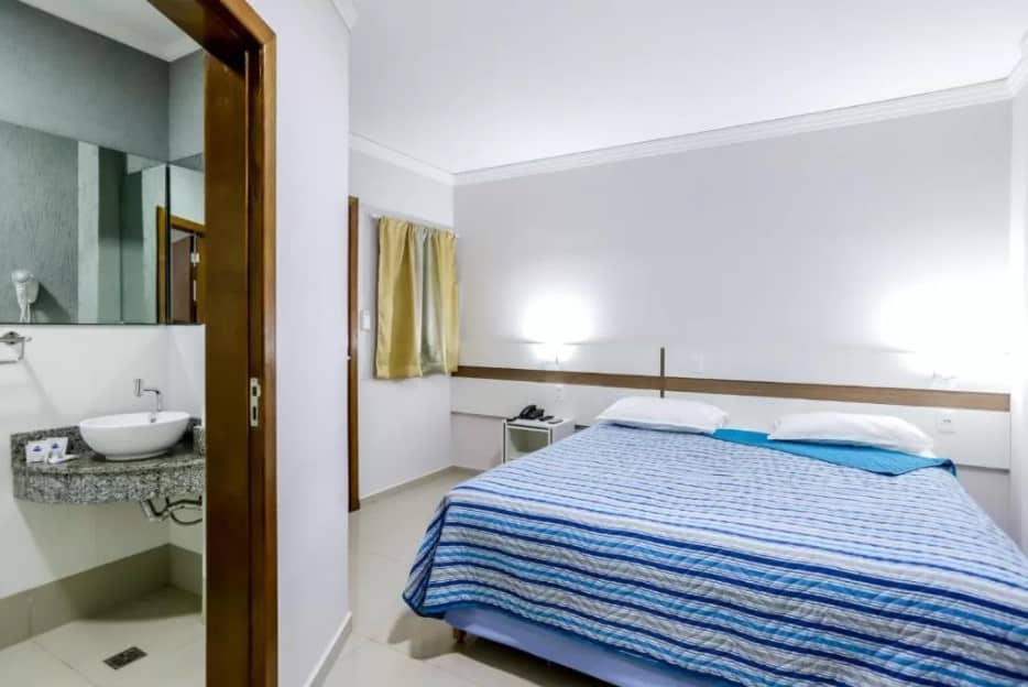 Quarto do Hotel Trevita Foz com uma cama de casal na parte direita do quarto e do lado esquerdo tem uma porta que dá acesso ao banheiro.