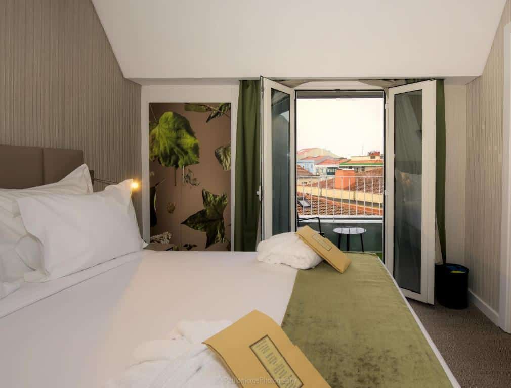 Quarto do The Leaf Boutique Hotel Lisbon com uma cama de casal e uma pequena varanda com uma mesinha e uma cadeira, para representar hotéis em Lisboa.