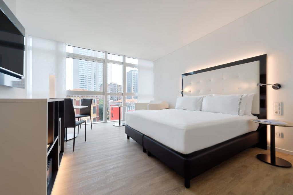 quarto amplo com escrivaninha, TV e cama grande, com janela que pegam a parede toda com vista da cidade no INNSiDE by Melia Milano Torre GalFa