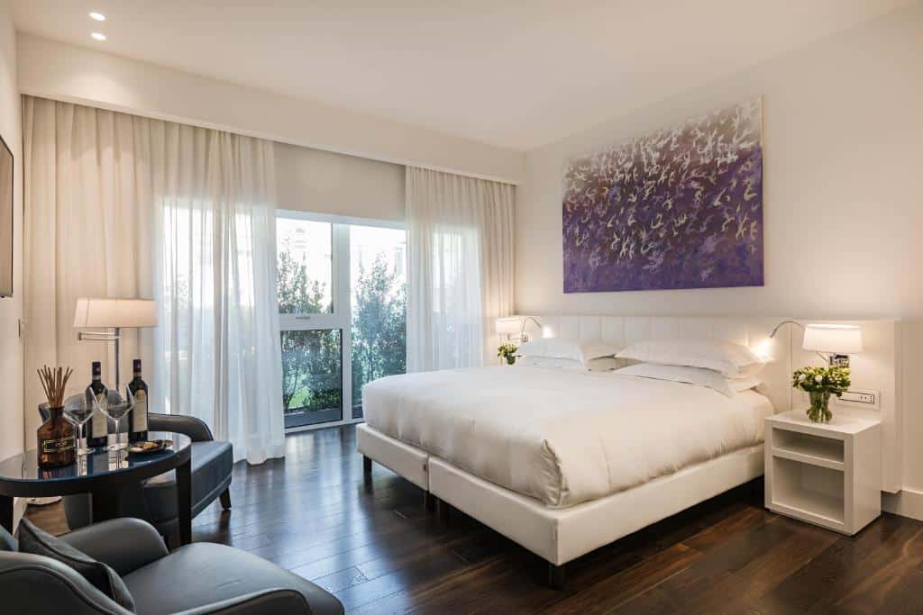 quarto amplo e delicado com cama grande, mesa e cadeira com janela grande de parede inteira no Magna Pars l'Hotel à Parfum