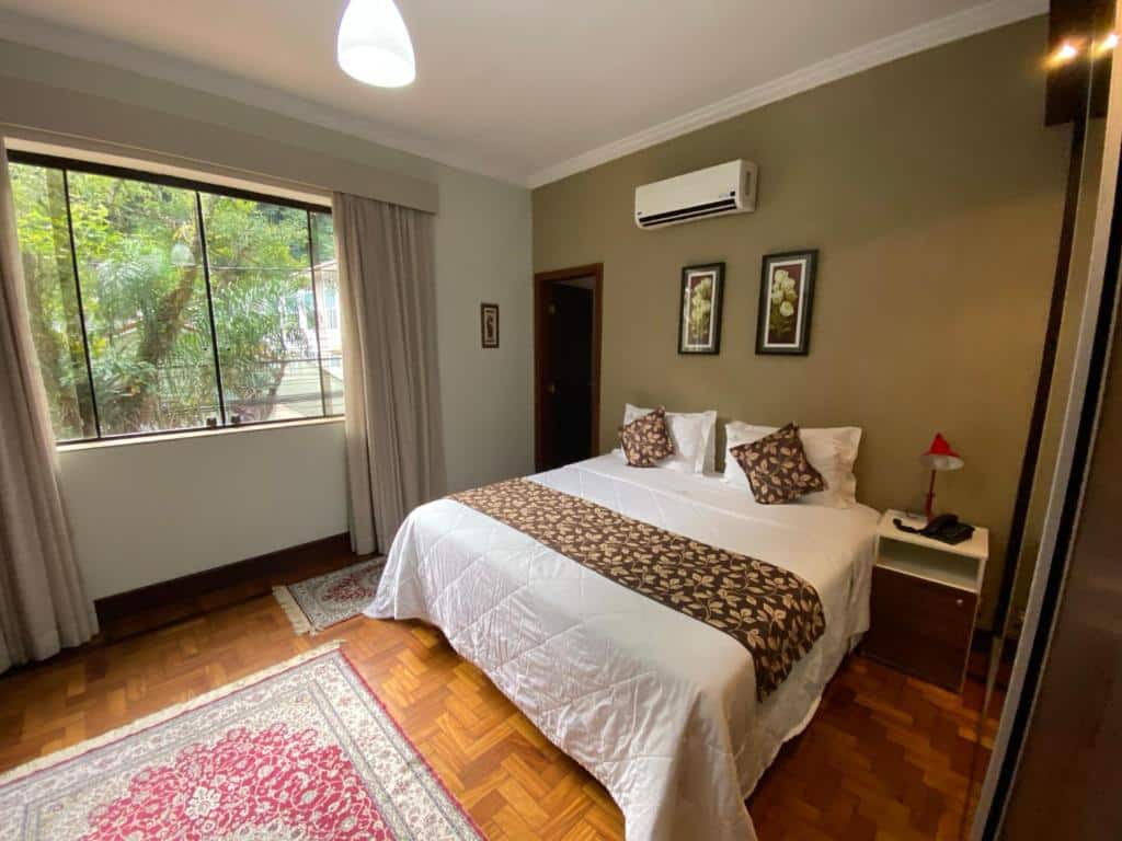 Quarto do Princesa Isabel Pousada e Hotel – Dom Pedro com uma janela com cortinas, chão de taco, um tapete, um ar-condicionado de teto e um armário com espelho