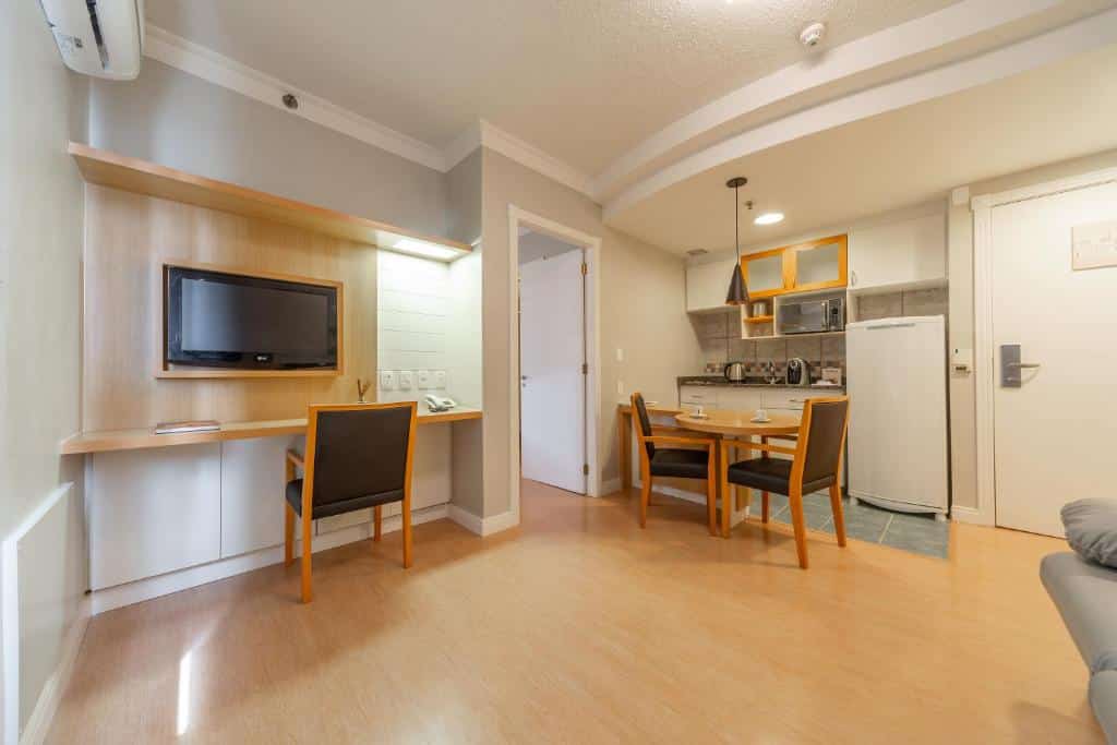 Acomodação do Laghetto Vertice Manhattan, um dos hotéis em Porto Alegre indicados, com área de mini cozinha, TV, ar-condicionado e uma porta para outro cômodo