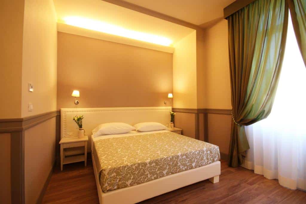 Quarto bege suavemente iluminado do DNB House Hotel em Roma com uma cama bem arrumada com dois travesseiros, mesas de cabeceira, luminárias de parede e cortinas verdes.