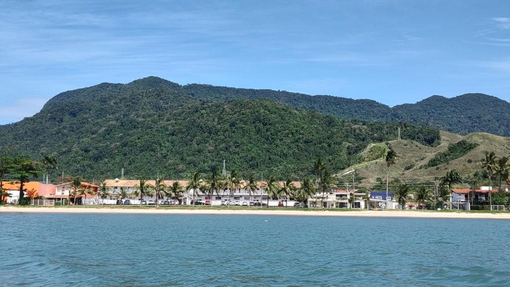 Imagem do mar de São Sebastião durante o dia a frente com o mar a frente ao fundo algumas casas e mais ao fundo montanhas.