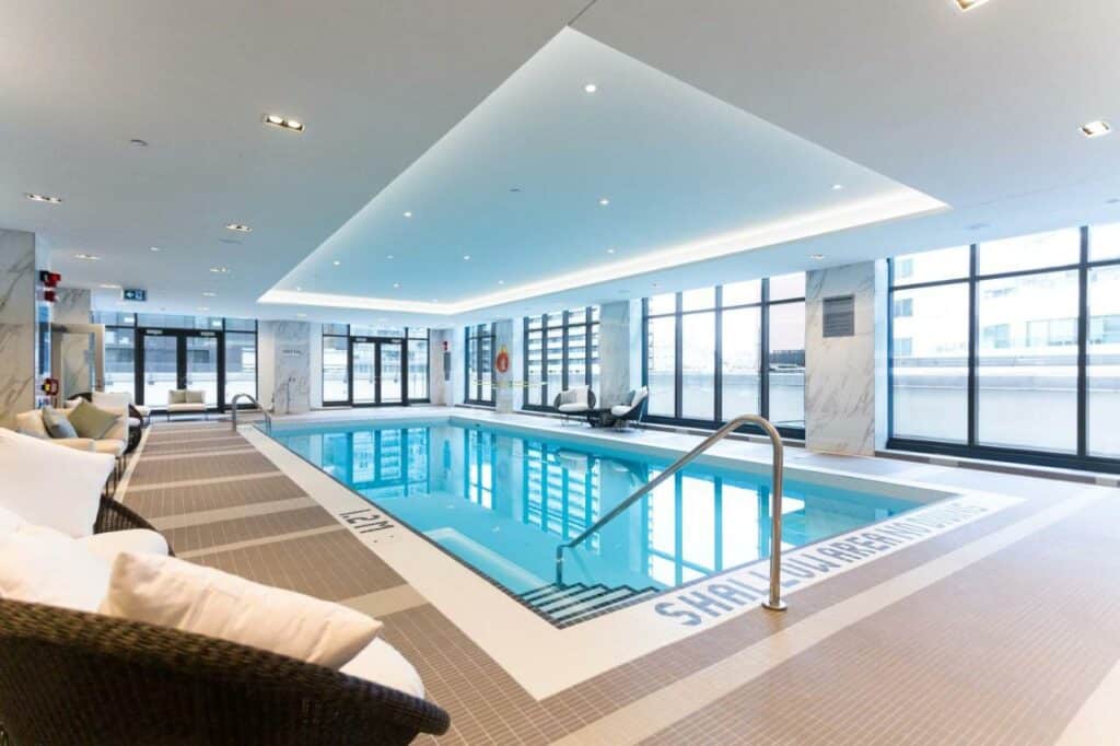 Piscina coberta do King Blue Hotel Toronto com um deck cercado por sofás