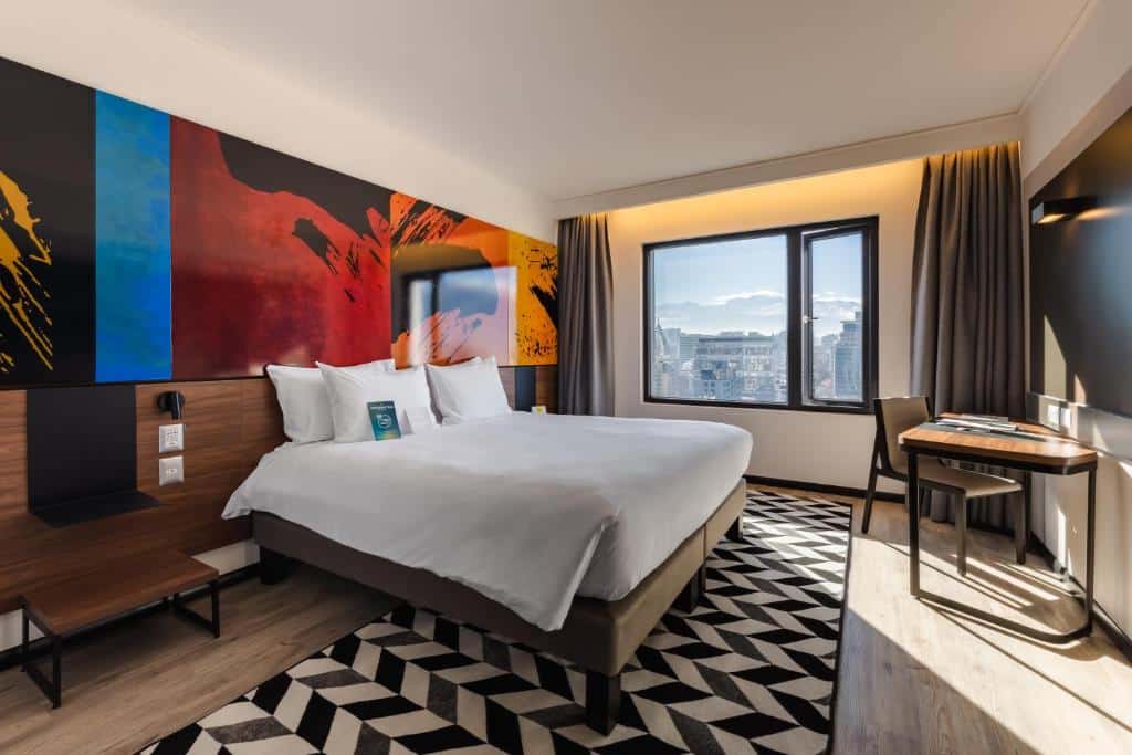 Quarto do Novotel Santiago Providencia com cama de casal do lado esquerdo, uma mesa de trabalho em frente a cama.