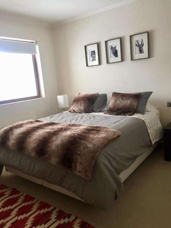 Quarto do Apartment Valle Nevado com cama de casal e três quadros de animais silvestre (um veado, uma raposa e um leão da montanha) em preto e branco, pendurados sobre a cama, na parede.