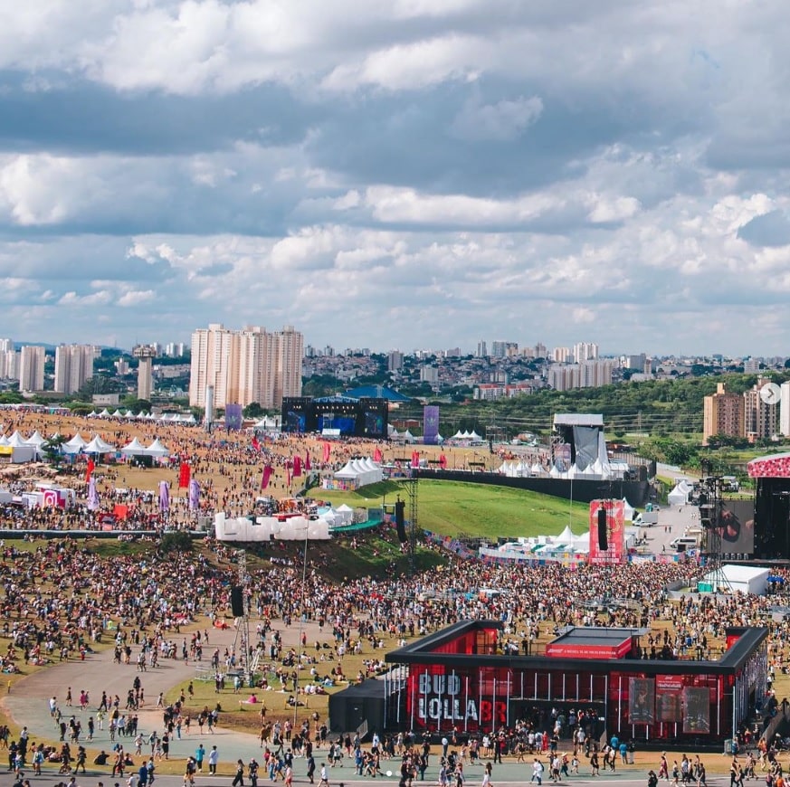 Vista aérea do Autódromo de Interlagos durante um dia de evento do Lollapalooza com muitas pessoas andando e palcos montados