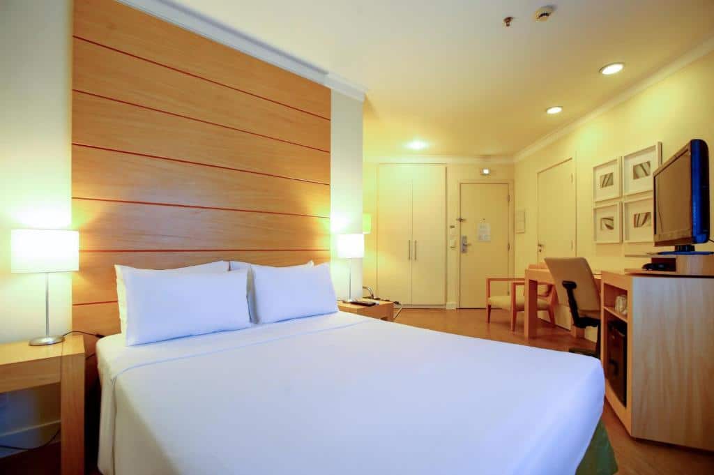 Quarto do eSuítes Congonhas by Atlantica com uma cama de casal, uma mesa de escritório com uma cadeira giratória, uma televisão e um armário, para representar hotéis para o The Town em SP