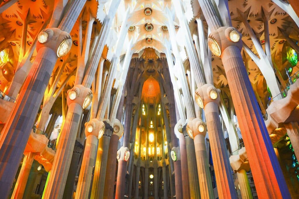 Interior da igreja da Sagrada Família. Diversos pilares beges se erguem até o teto do local. - Foto: Sung Jin Cho via Unsplash