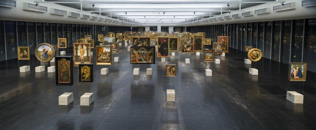 Obras expostas em um amplo espaço dentro do museu com quadros suspensos, no MASP (Museus de Arte de São Paulo).