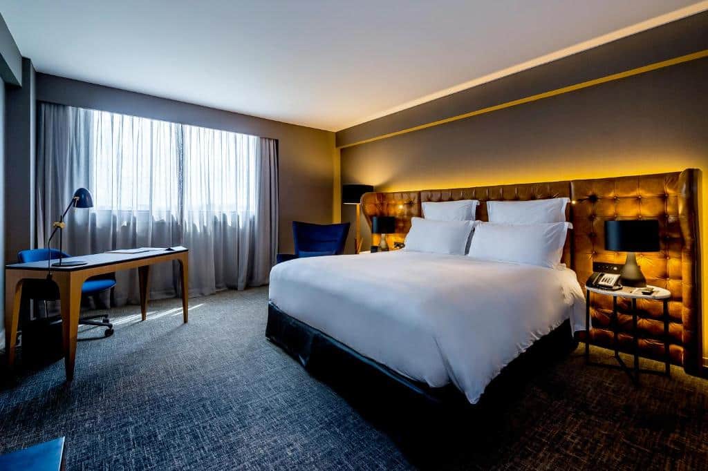 Quarto do Pullman Sao Paulo Guarulhos Airport, um dos hotéis perto do Aeroporto de Guarulhos, com cama de casal, mesa de trabalho, mesinhas de cabeceira e iluminação intimista.