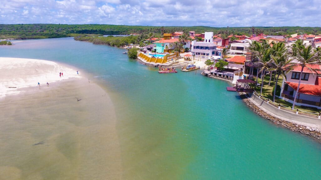 Vista de cima do mar da cidade de Aquiraz, Ceará com casas em volta e mar azul turquesa.