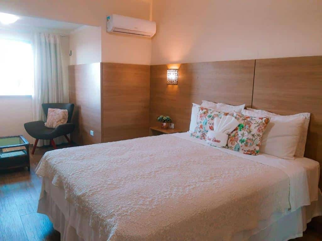 Quarto do Planet Dunas Residence com cama de casal, uma cômoda do lado esquerdo e uma poltrona perto da janela, para representar hotéis perto do Beach Park.