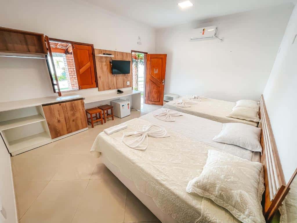 Quarto da Pousada Vasto Horizonte, com duas camas de casal, ar-condicionado, TV, frigobar e pequenos armários, para representar pousadas em Barreirinhas.