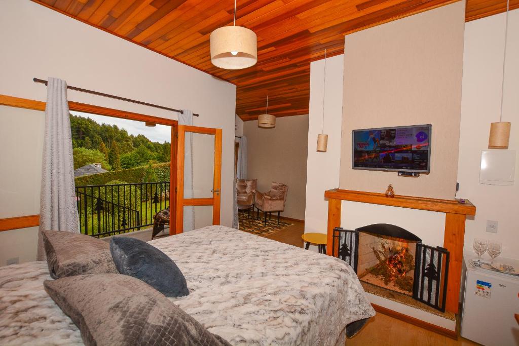 Um quarto aconchegante com camas de solteiro, lareira, TV na parede e uma varanda com vista para a vegetação, na Pousada Cantinho de Monte Verde.
