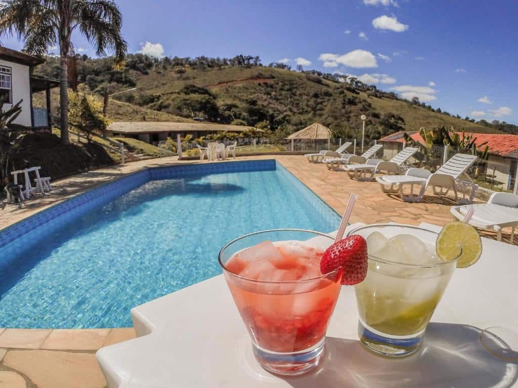 Piscina da Pousada Campestre São Lourenço, com um deck com cadeiras ao redor, com vista para as montanhas