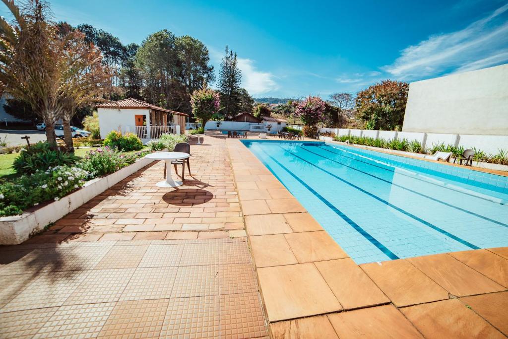 Piscina da Pousada Montanhas do Sol, local amplo, piscina grande, cercada por muita natureza e um jardim